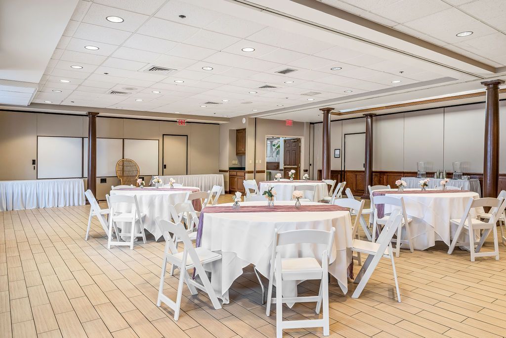 A large room with tables and chairs set up for a wedding reception.