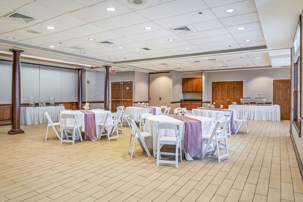 A large room with tables and chairs set up for a wedding reception.