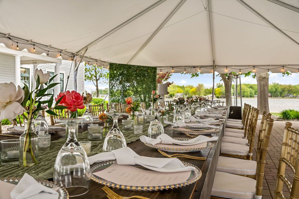 A long table set for a wedding reception under a tent.