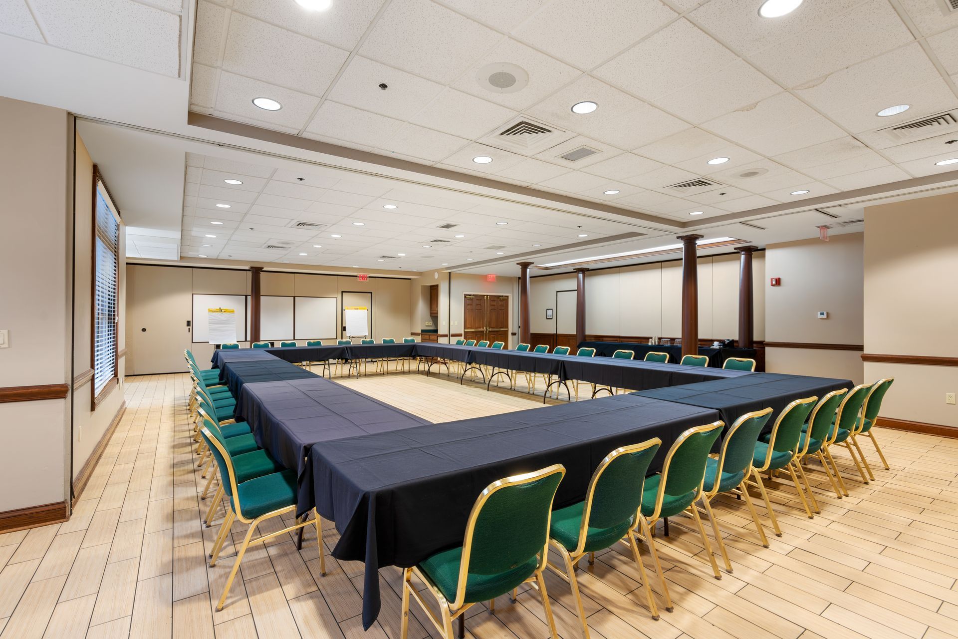 A large conference room with tables and chairs arranged in a u shape.
