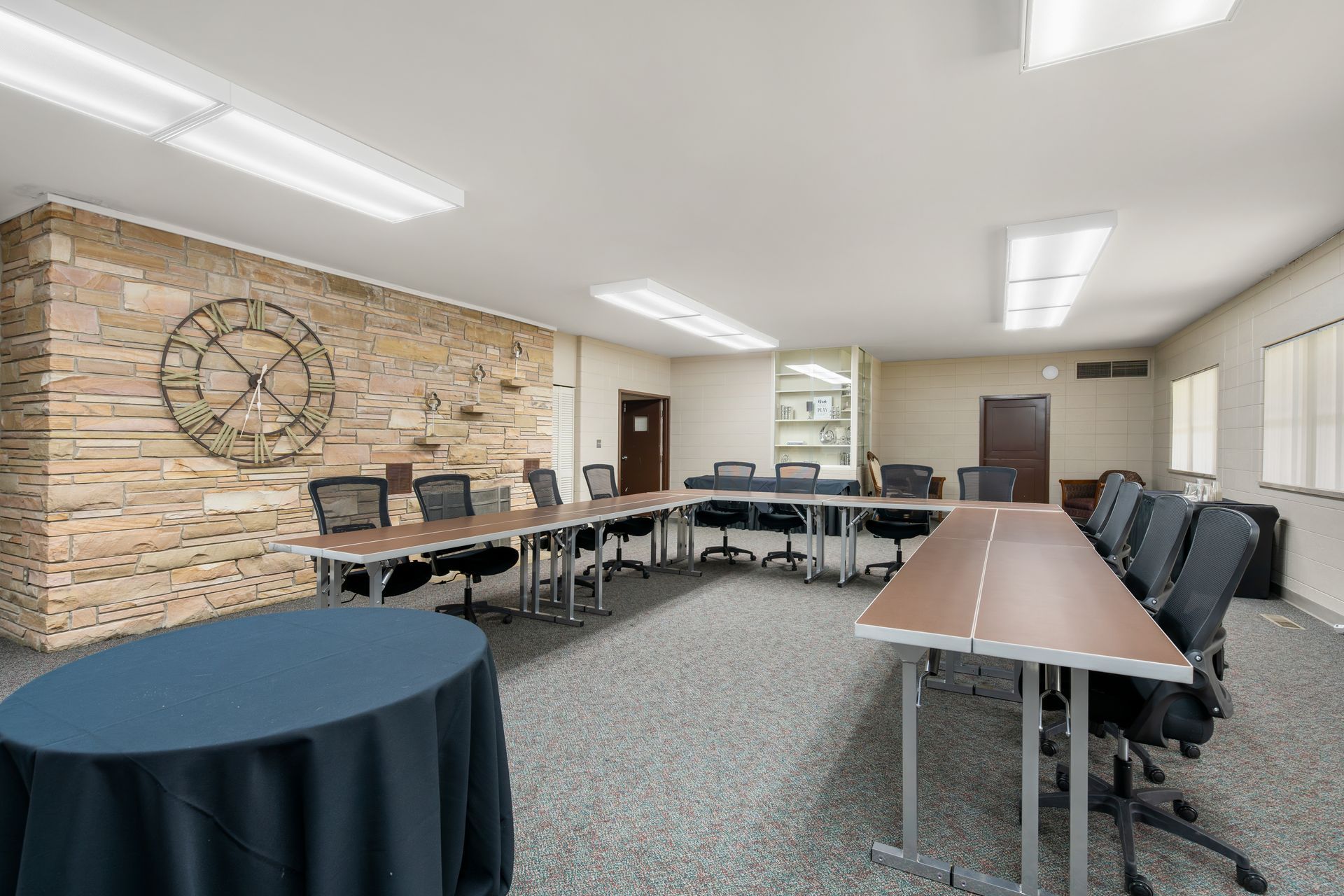 A conference room with tables and chairs and a clock on the wall.