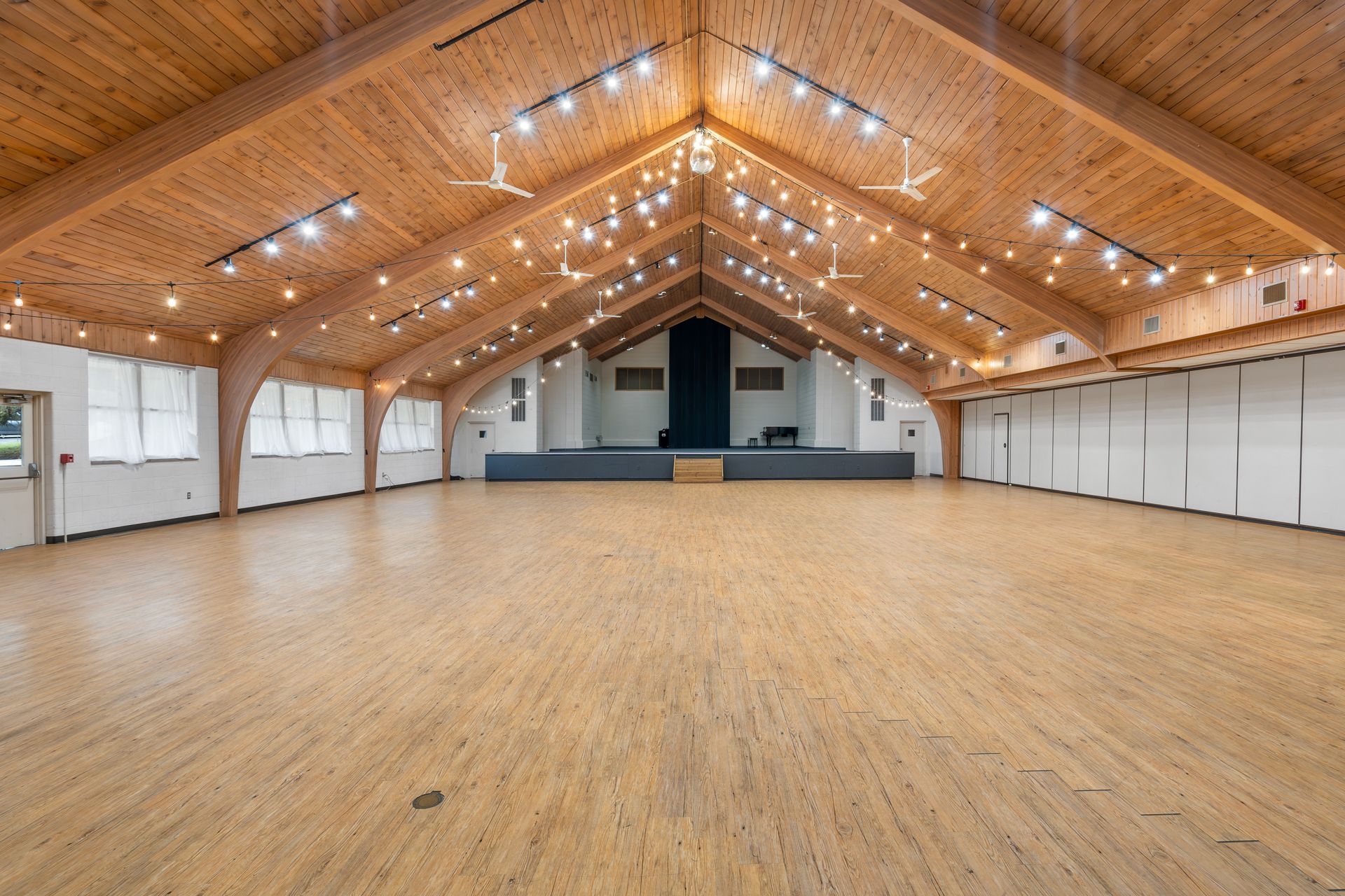 A large empty room with a wooden floor and a wooden ceiling.