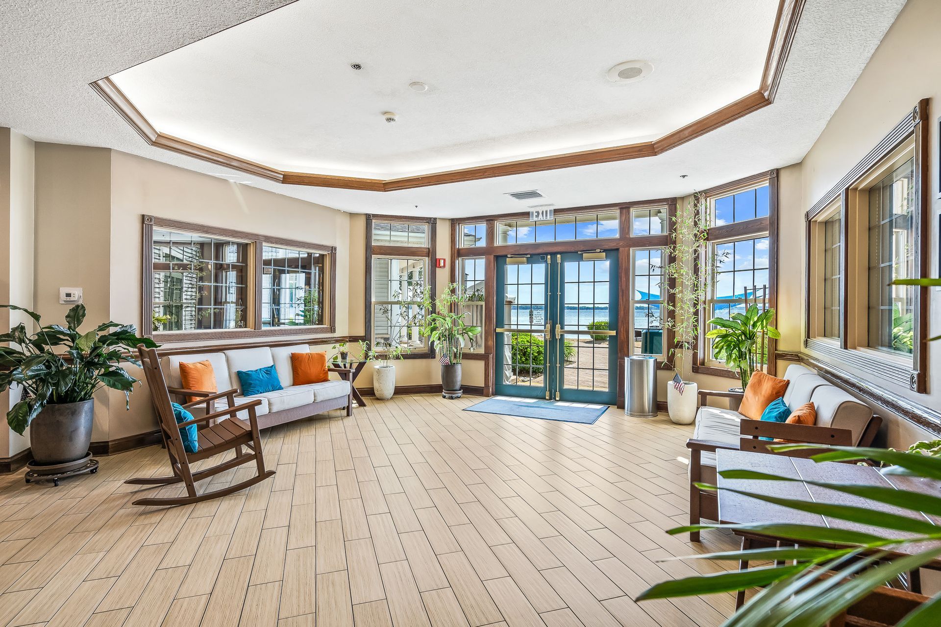 A large lobby with a couch , rocking chair , and plants.