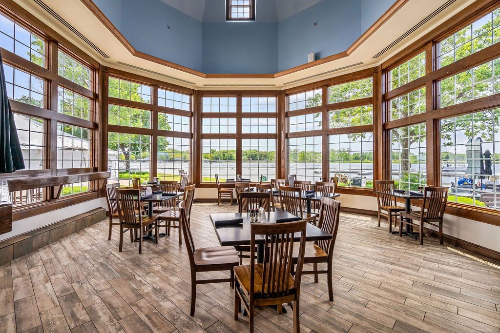 A large room with tables and chairs and a lot of windows.