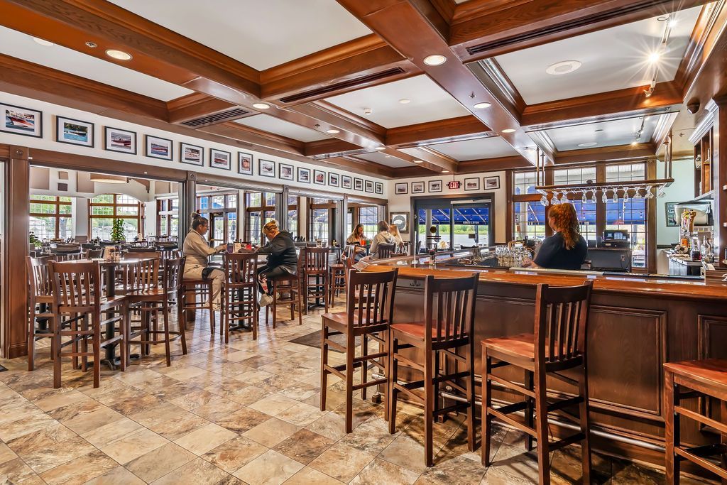 A restaurant with tables and chairs and a bar.