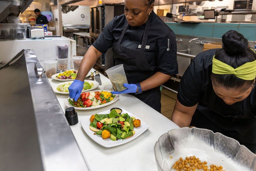 Two women are preparing food in a kitchen.