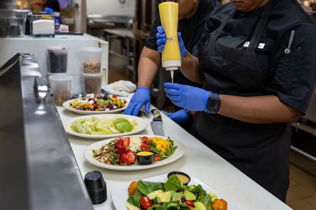Two chefs are preparing a salad in a restaurant kitchen.
