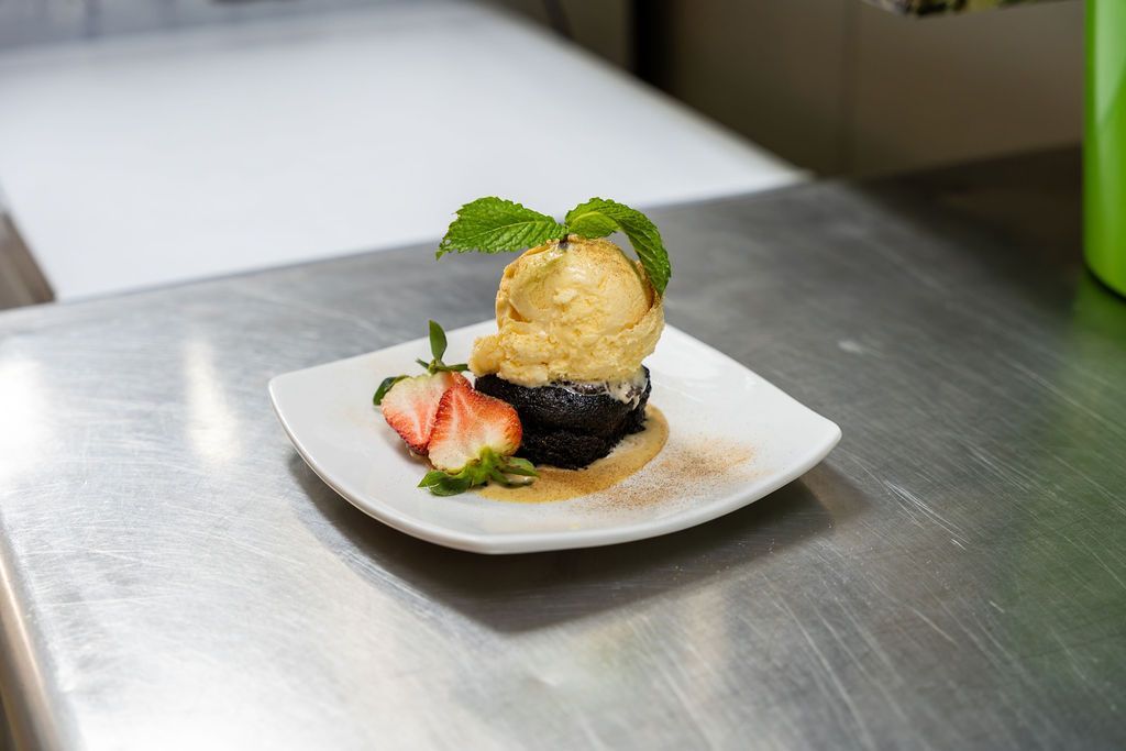 A dessert with ice cream and strawberries on a plate on a table.