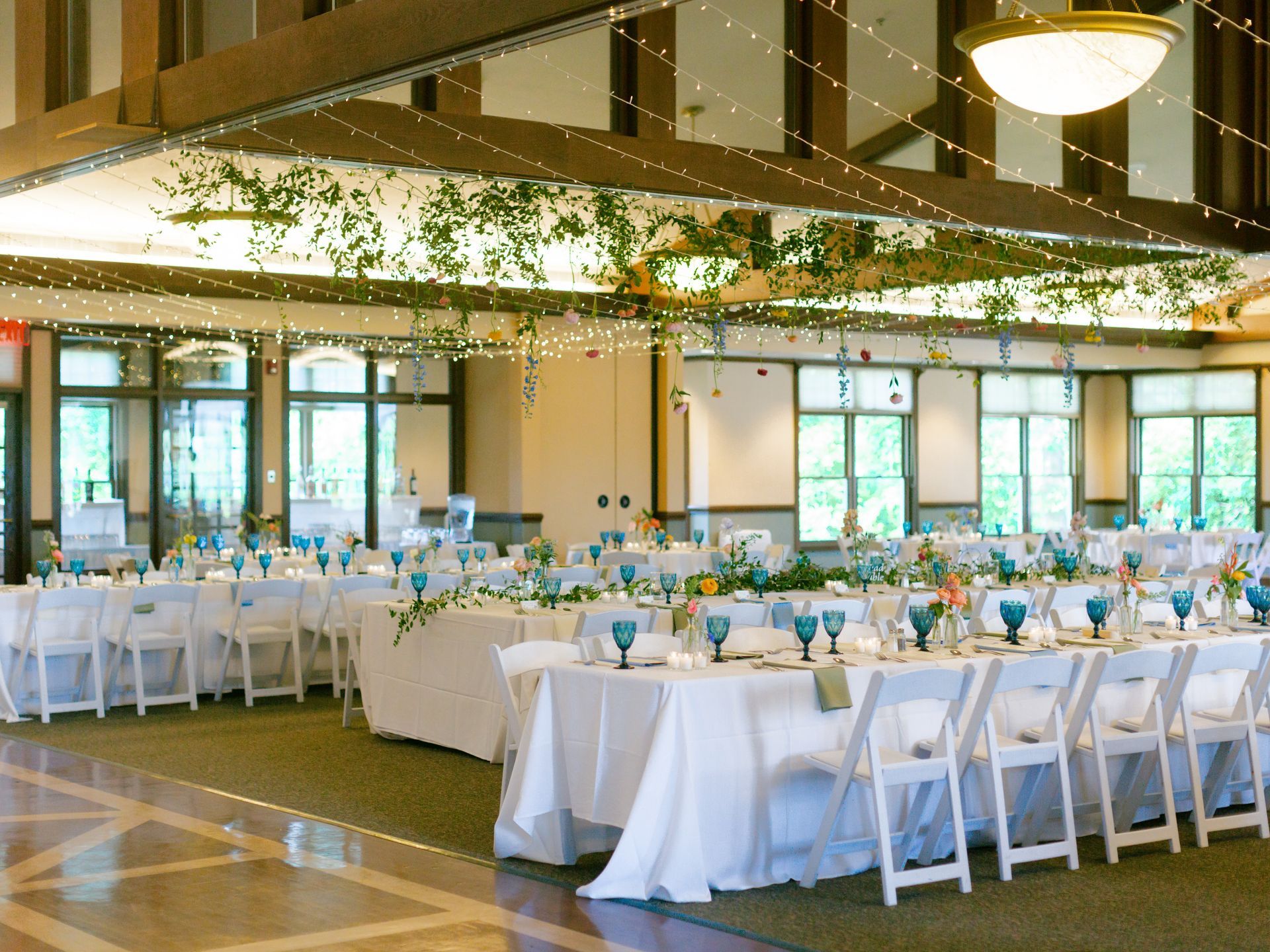 A large room with tables and chairs set up for a wedding reception