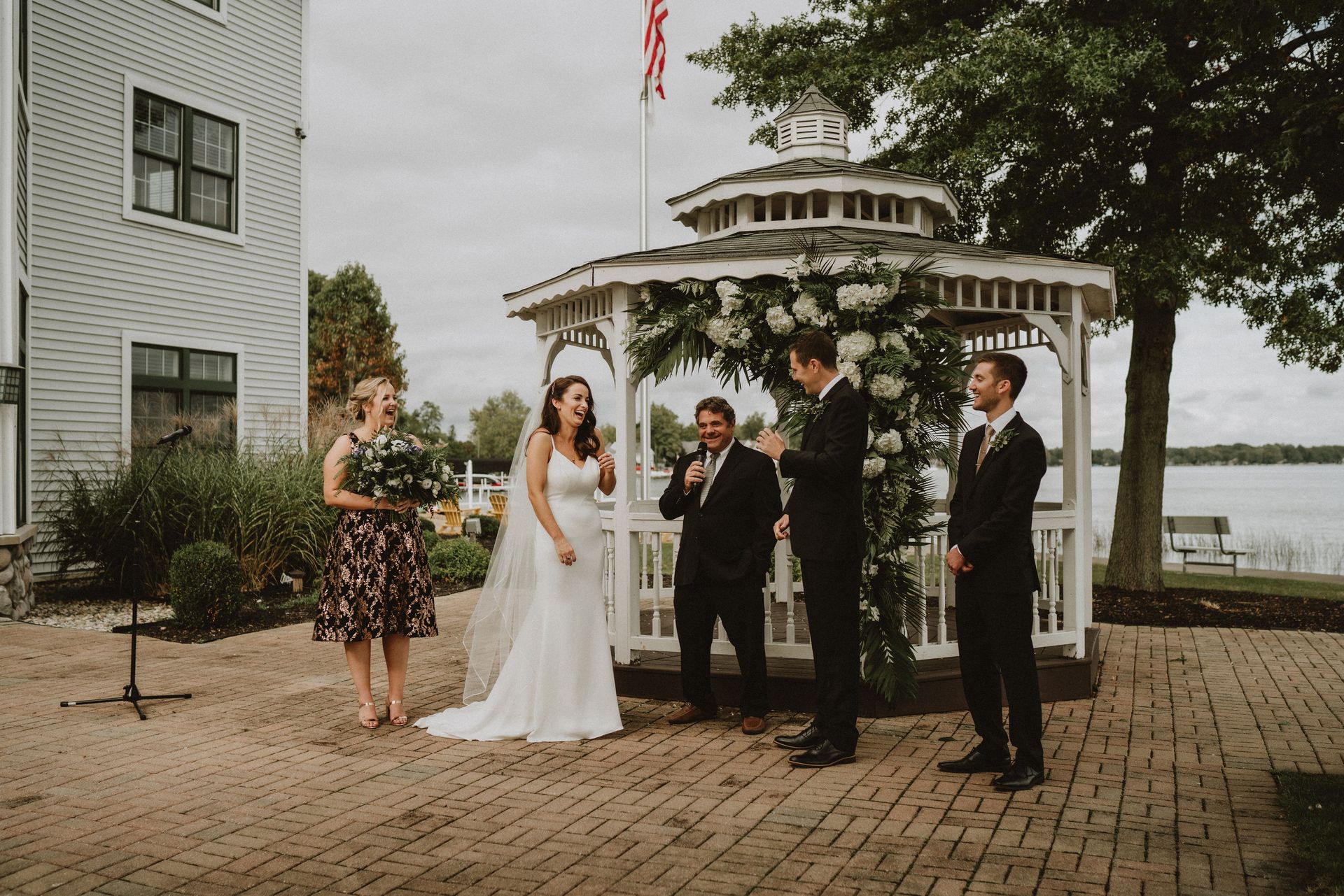 A bride and groom are standing in front of a gazebo during their wedding ceremony.