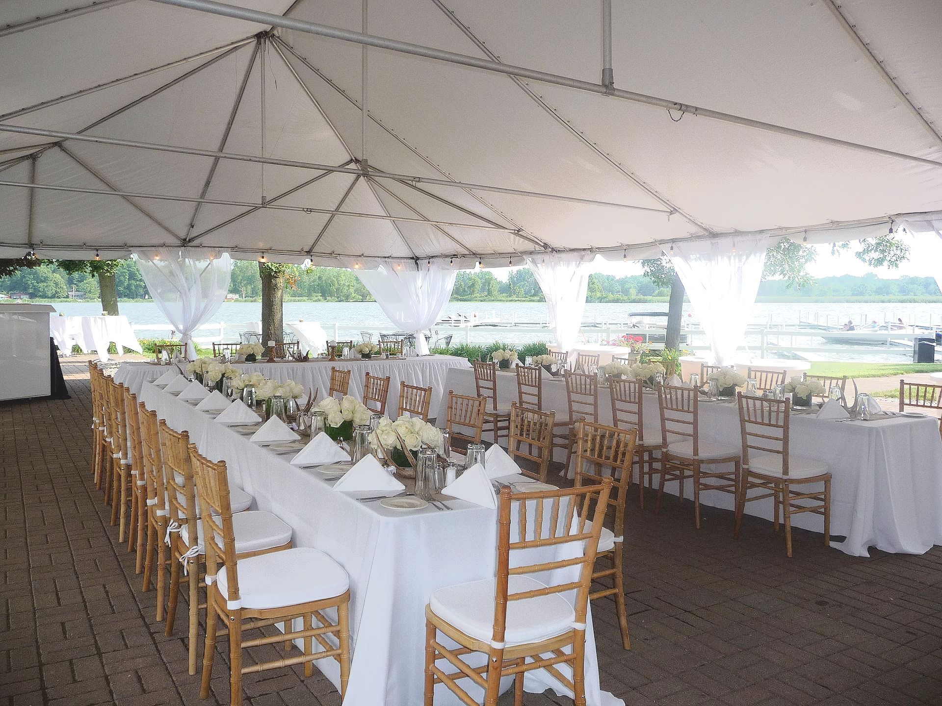 A long table and chairs under a tent with a lake in the background