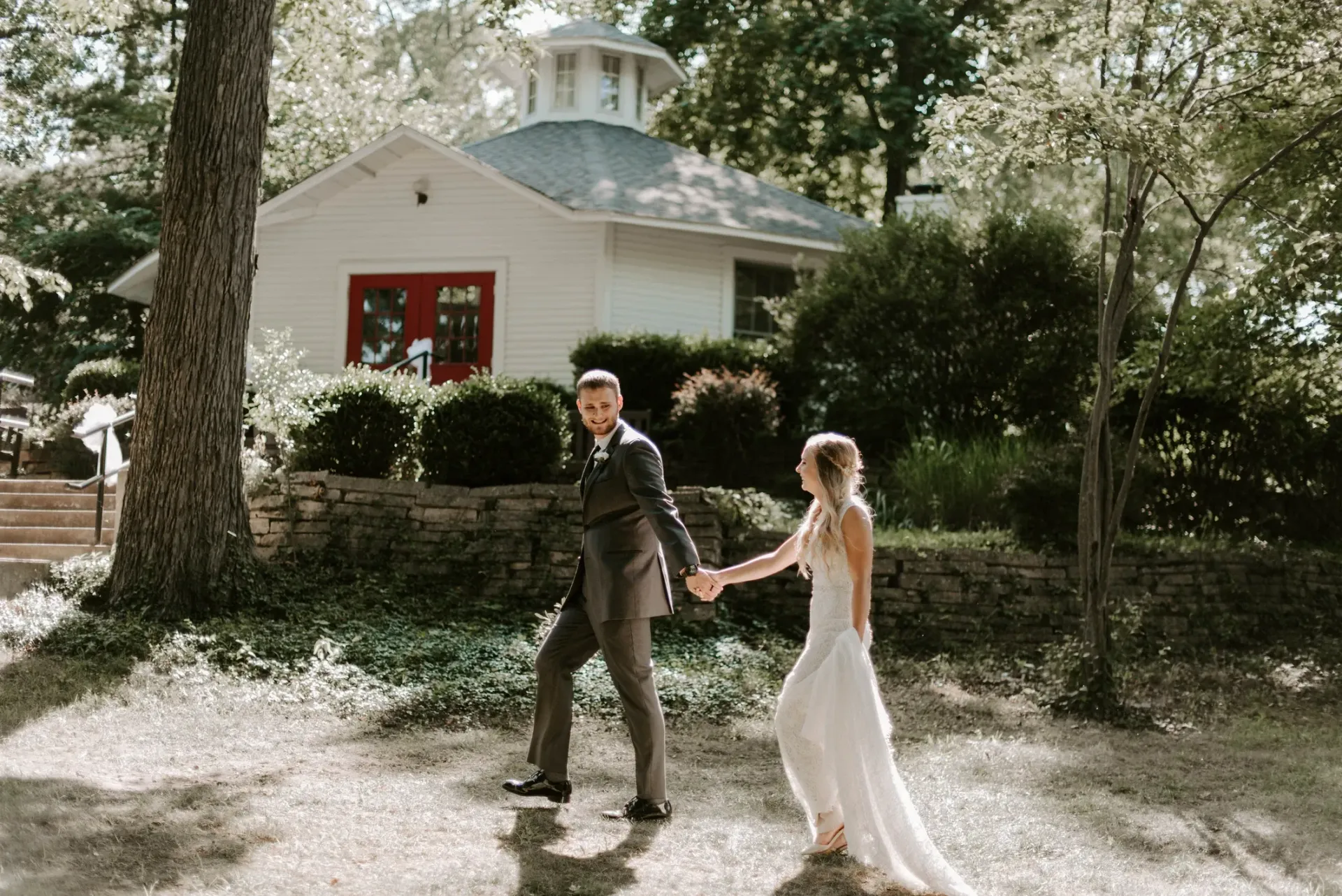 A bride and groom are holding hands in front of a white building.