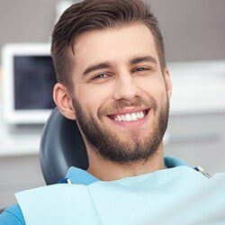 Teeth Cleaning — Man Smiling While Sitting in Dental Chair in Burlington, IA