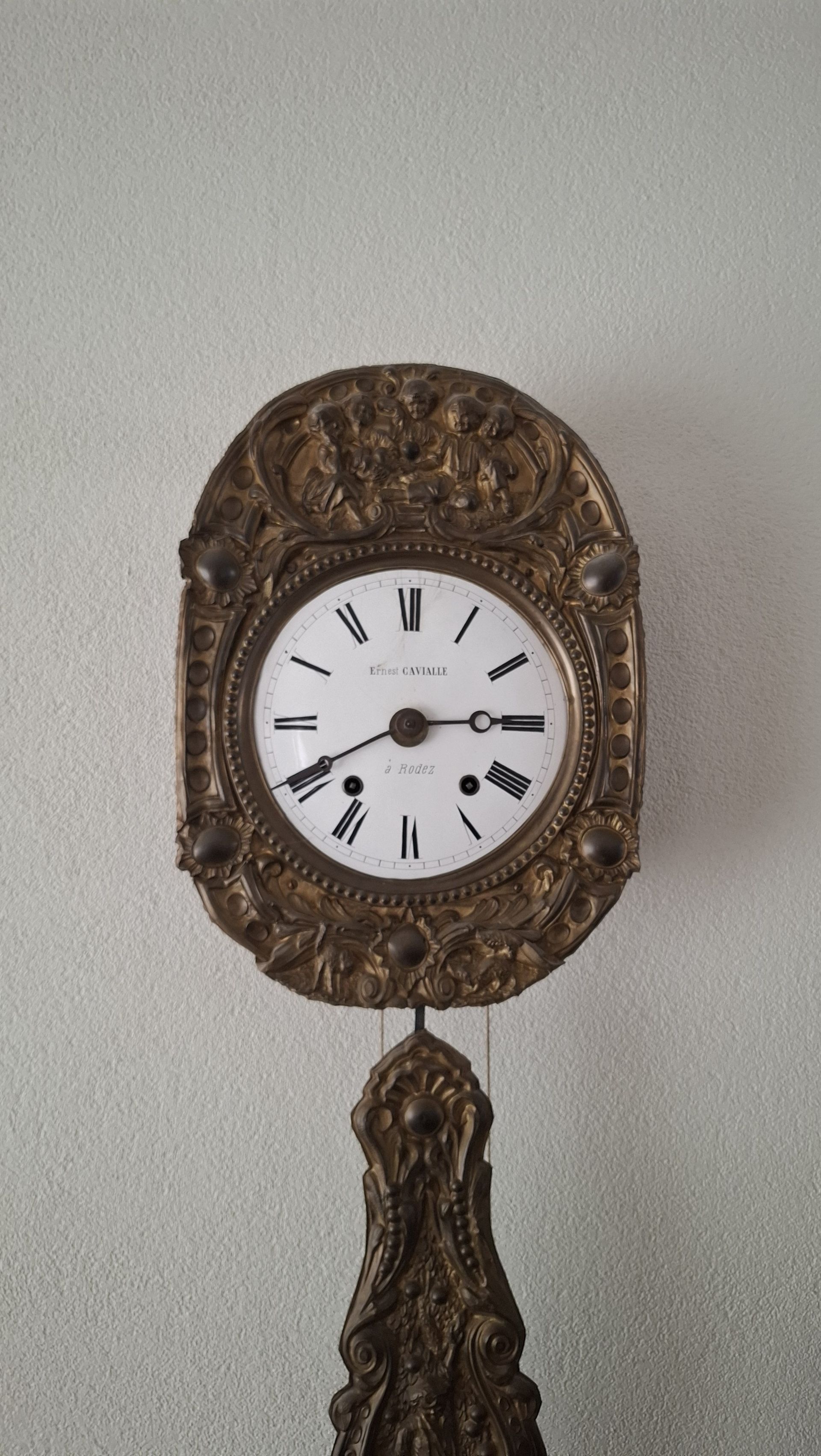 Sierlijke antieke klok met witte wijzerplaat, Romeinse cijfers en slinger.