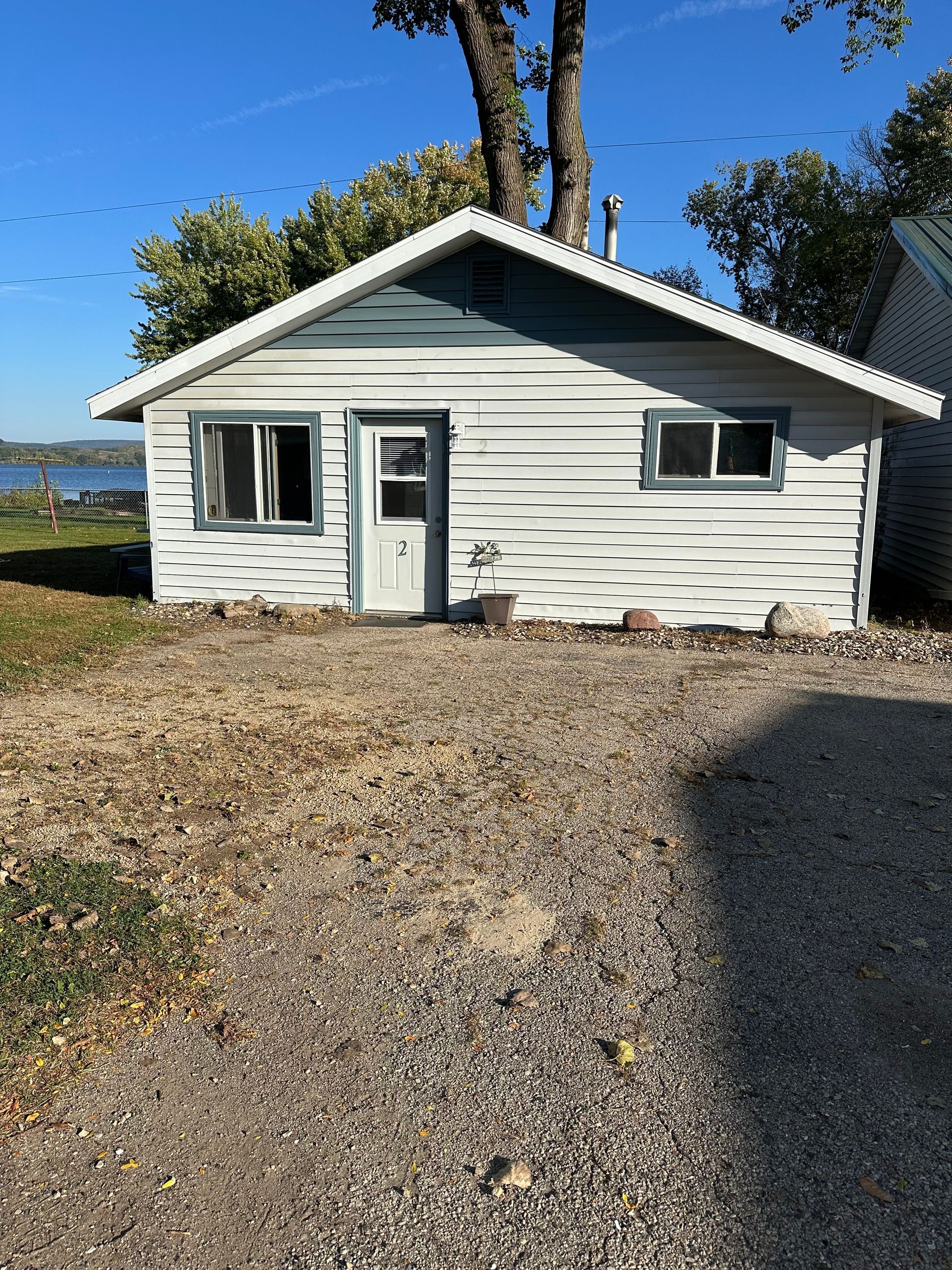 Small weathered cottage with blue trim, door, and windows, gravel yard.
