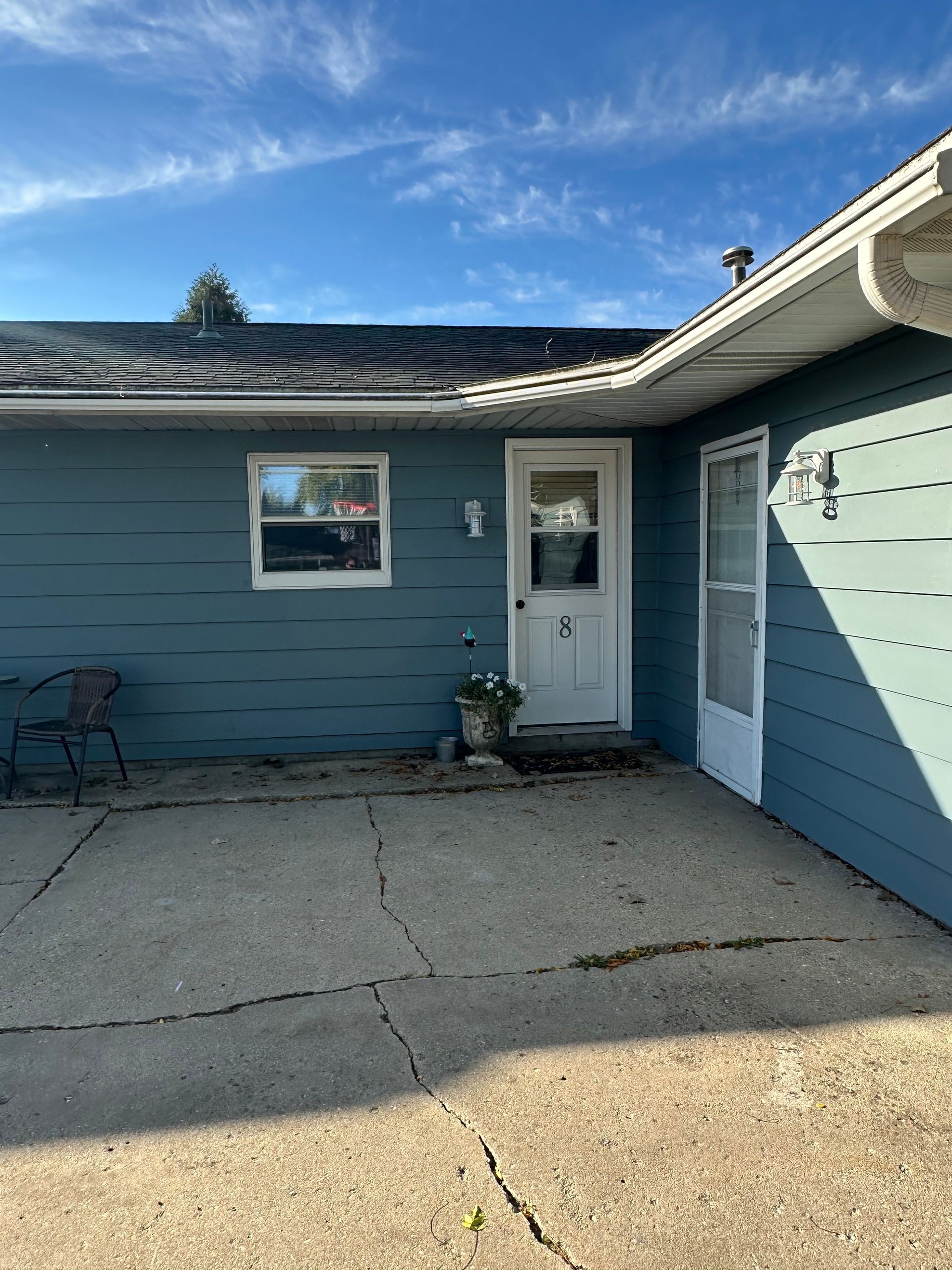 Blue house exterior with white trim, door, and patio.