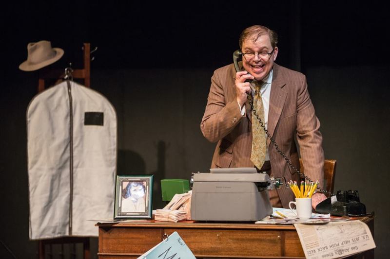 Bernie standing at his desk and talking on the phone.