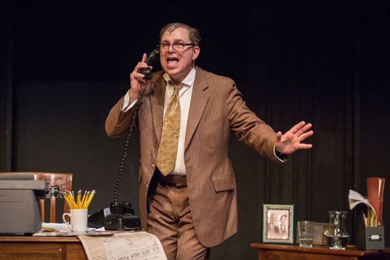 Bernie standing behind desk talking on the phone and looking happy.