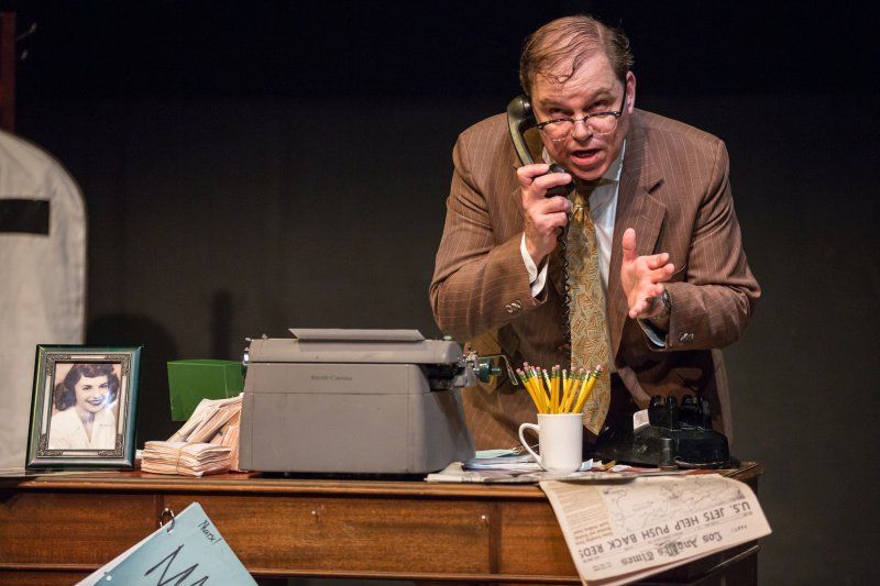 Bernie standing behind his desk making a point while talking on the phone.