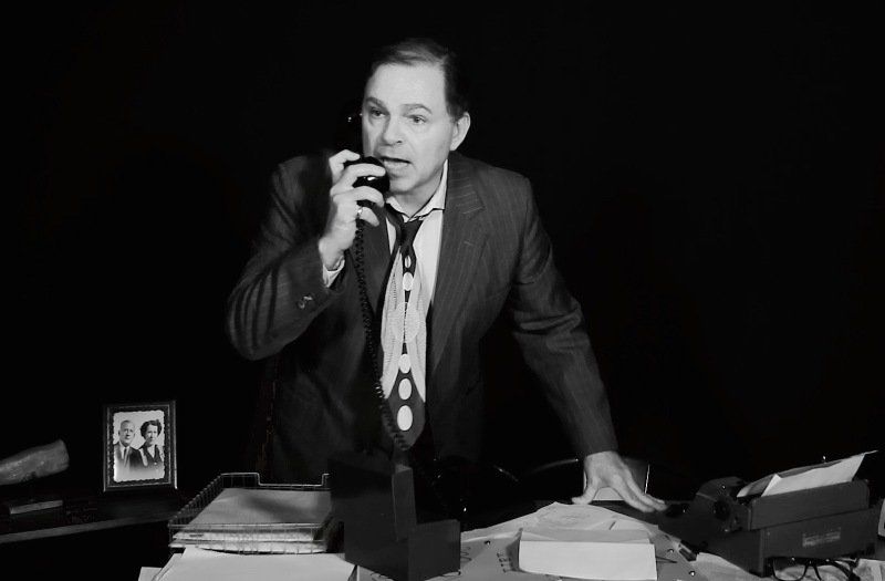 Bernie talking excitedly on phone he's holding in right hand