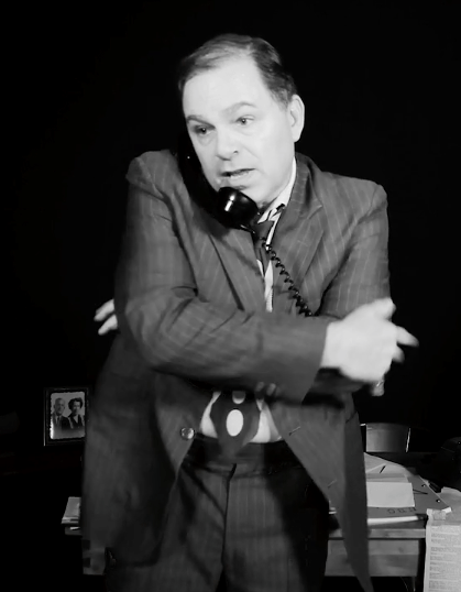 Bernie Lutz  listening on phone as he stands with his hands across his body