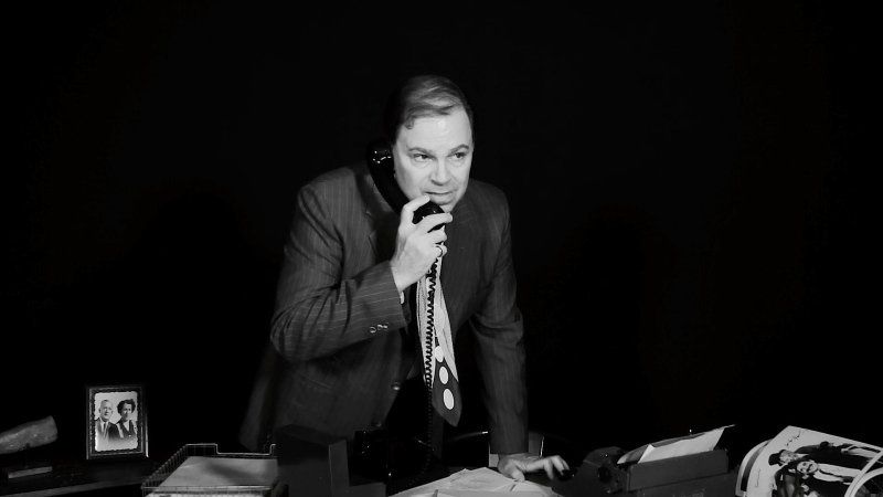 Bernie leans over his desk while on phone