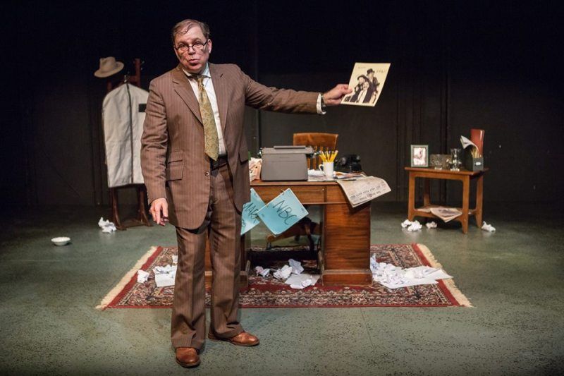 Bernie standing in front of his desk and holding a picture of the Marx Brothers.