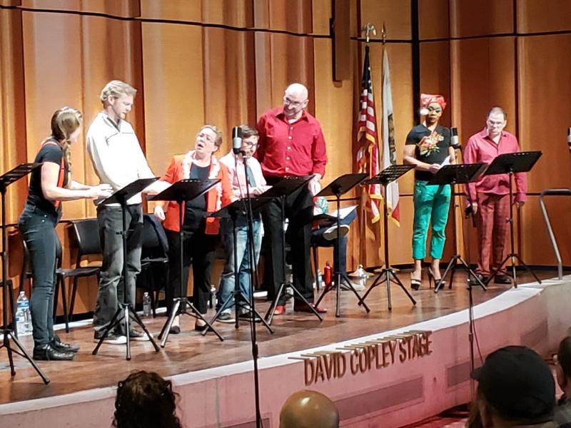 7 actors at music stands on stage during  a scene