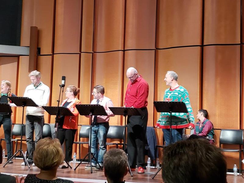 6 actors laughing while standing at black music stands