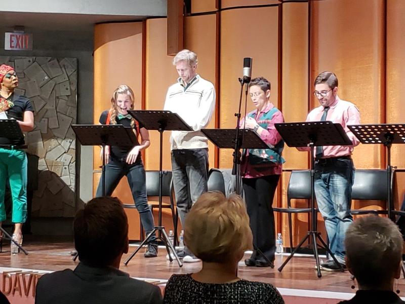 5 actors standing at music stands  during play reading at San Diego Main Library auditorium