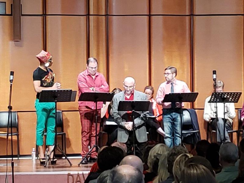 7 actors standing at music stands or seated during play reading