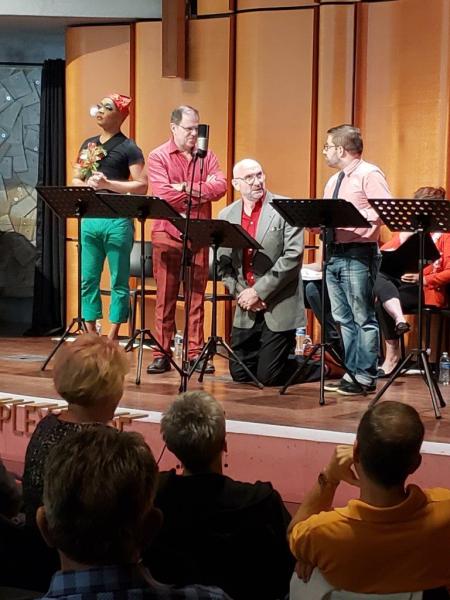 3 attendees watching 4 actors at music stands on stage