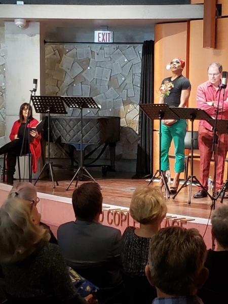 1 actor in red sweater seated 2 actors standing at music stands