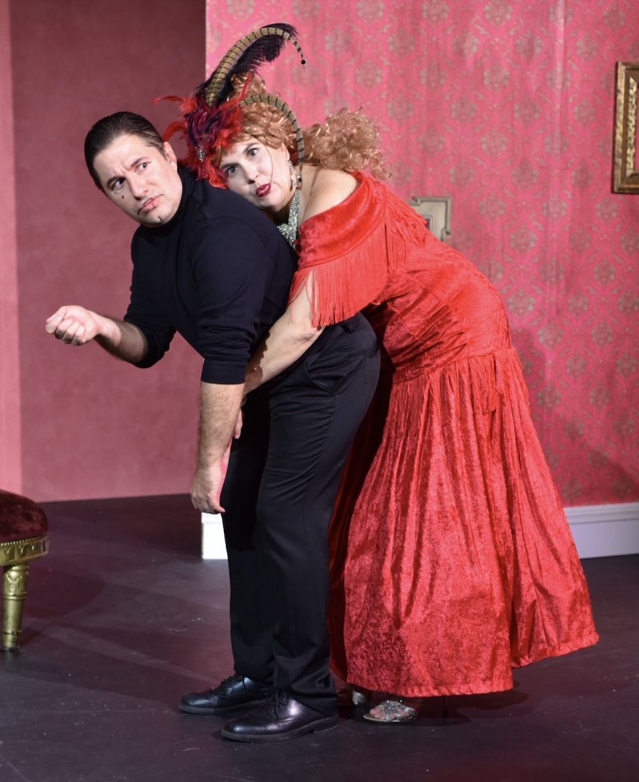 A woman in a red dress is hugging a man  in a black shirt from behind