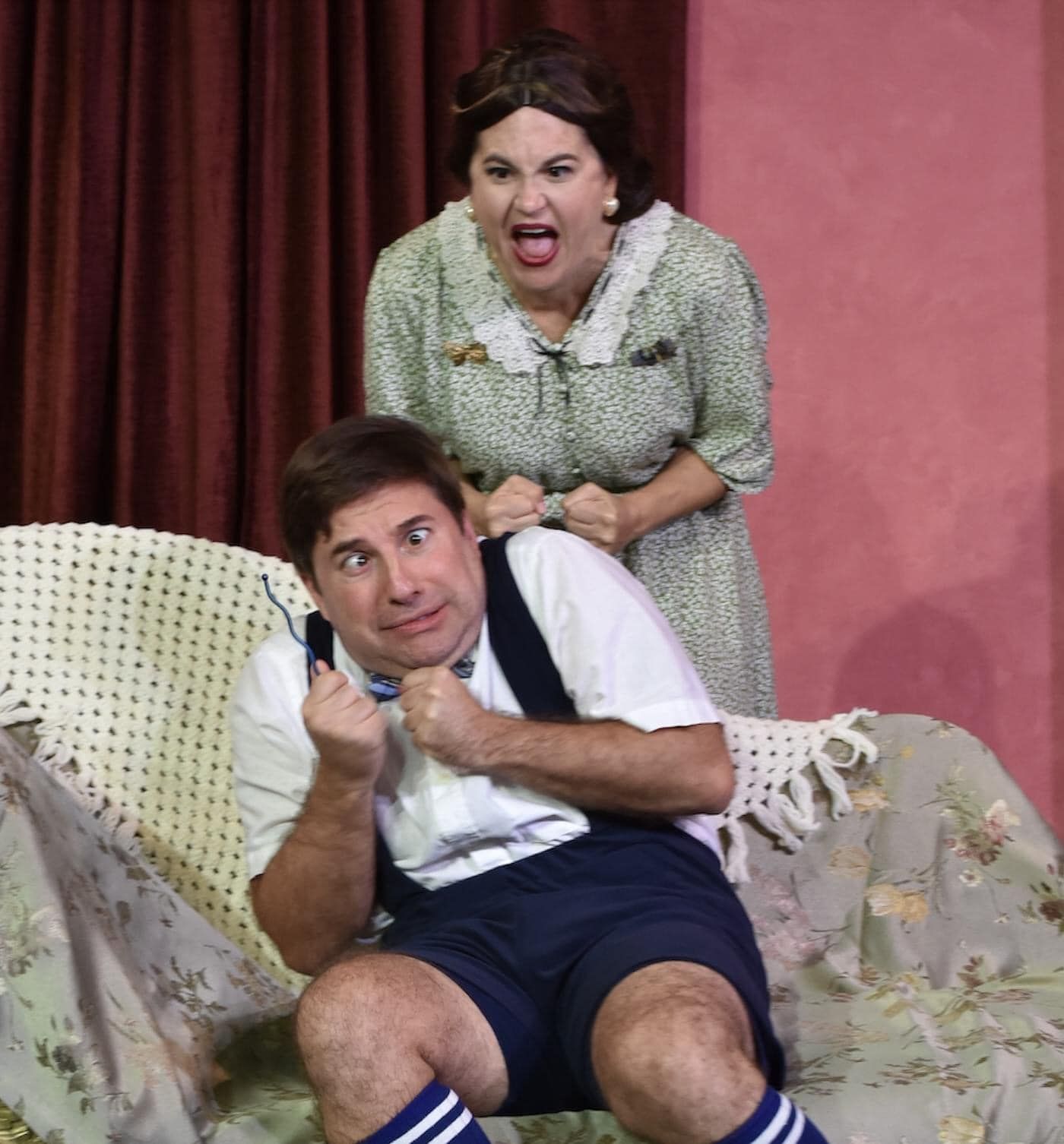 A woman is standing behind a man sitting on a couch