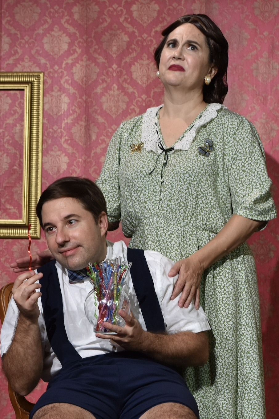 A woman is standing next to a man holding a vase of flowers .