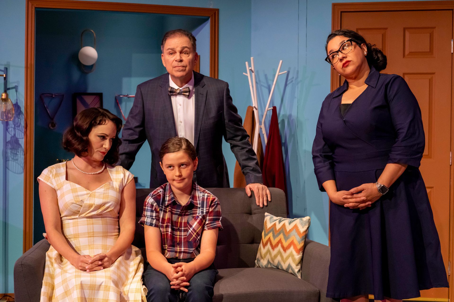 A group of people are standing around a couch in a living room .