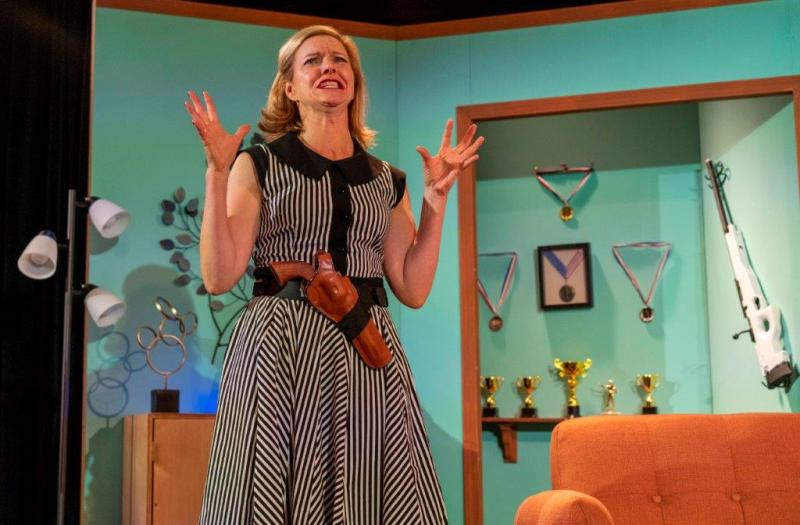 Mother in black and white striped dress and gun belt looking very unhappy.