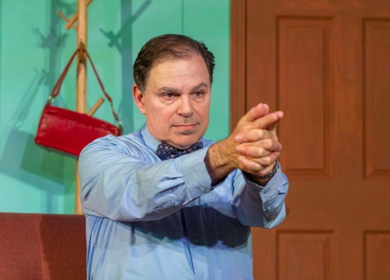 Father in blue shirt pointing a pretend finger gun.