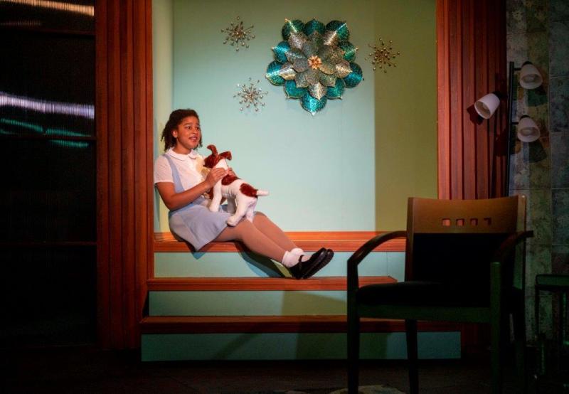 Young daughter in blue and white dress sitting on steps and holding her  dog.