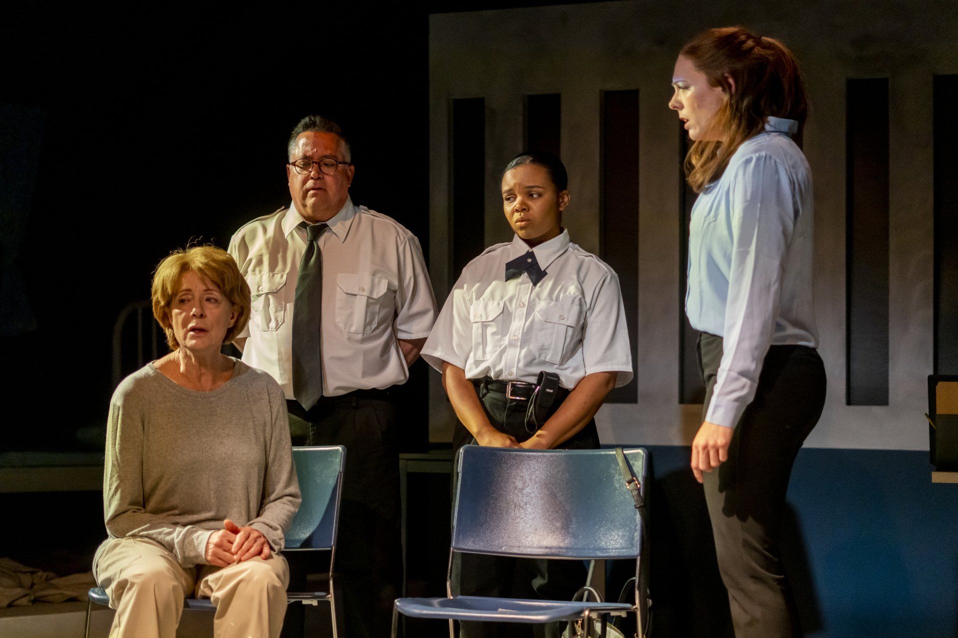 A group of people are standing next to a woman saitting in a chair on a stage.