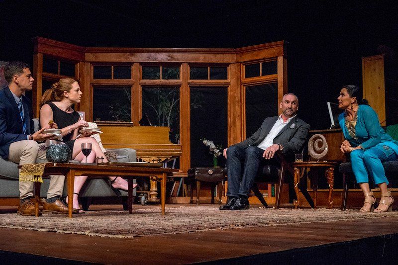 Couple on sofa eating, seated man in grey suit and woman in blue  talking