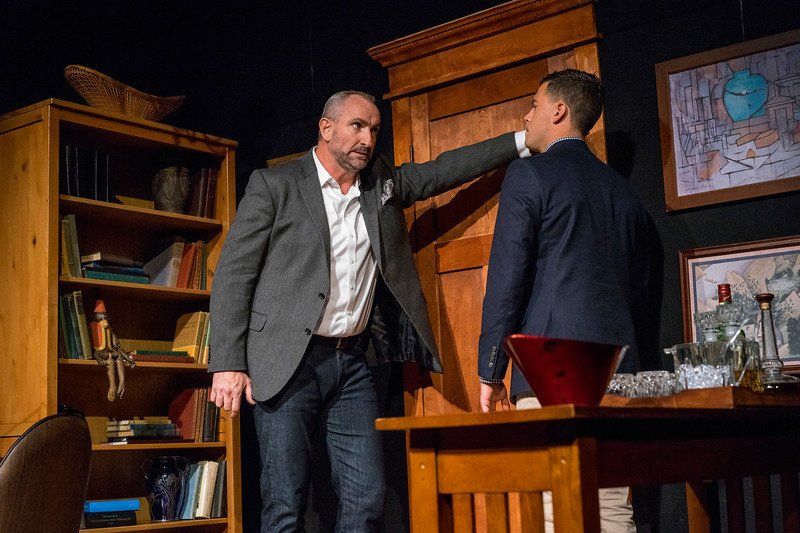 Man in grey suit jacket looking angrily at man in blue suit jacket