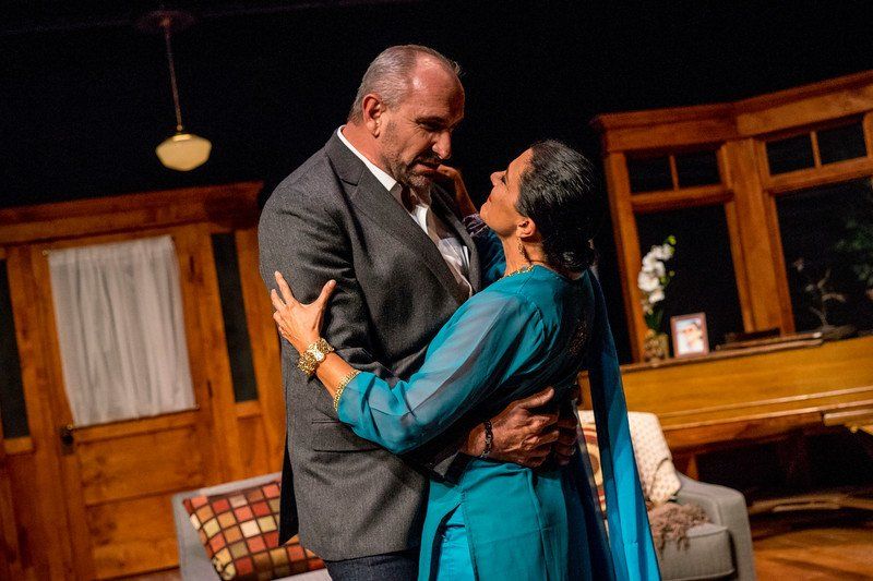Man in grey suit jacket embracing woman in blue outfit