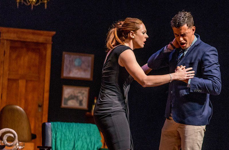 Man in blue suit jacket and woman in black dress arguing and looking unhappy