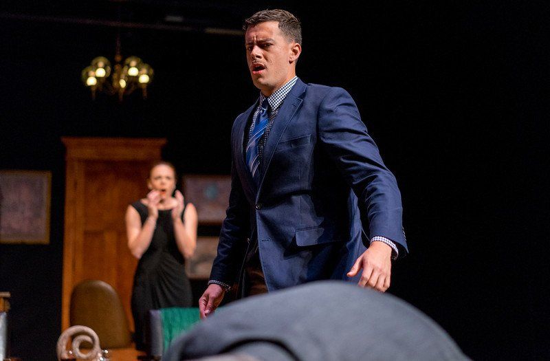 Woman in black dress in blurred background with man in blue suit jacket in close-up
