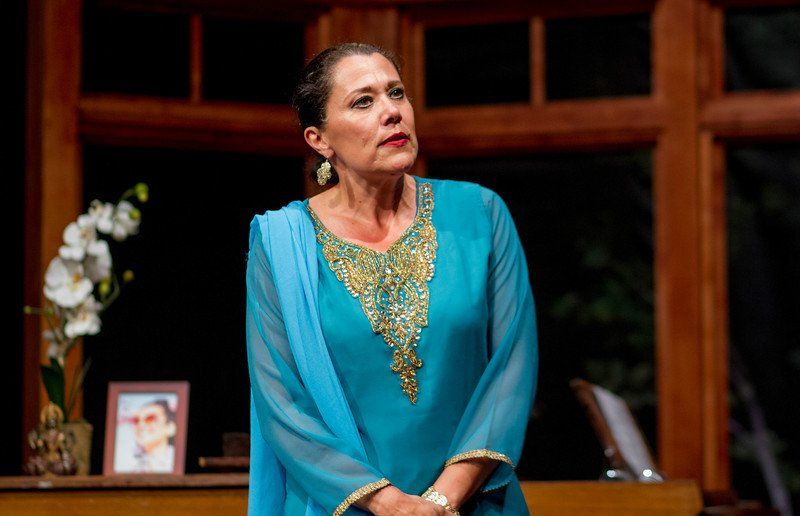 Standing woman wearing beautiful blue outfit with gold trim at neckline