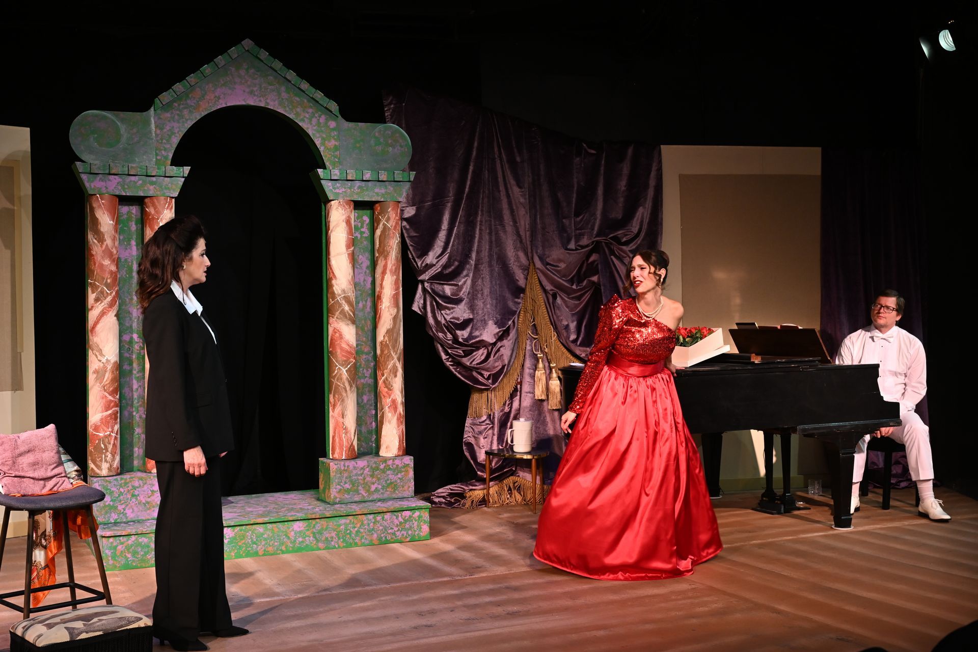 Stage scene with woman in red gown singing, pianist, and woman in black suit.