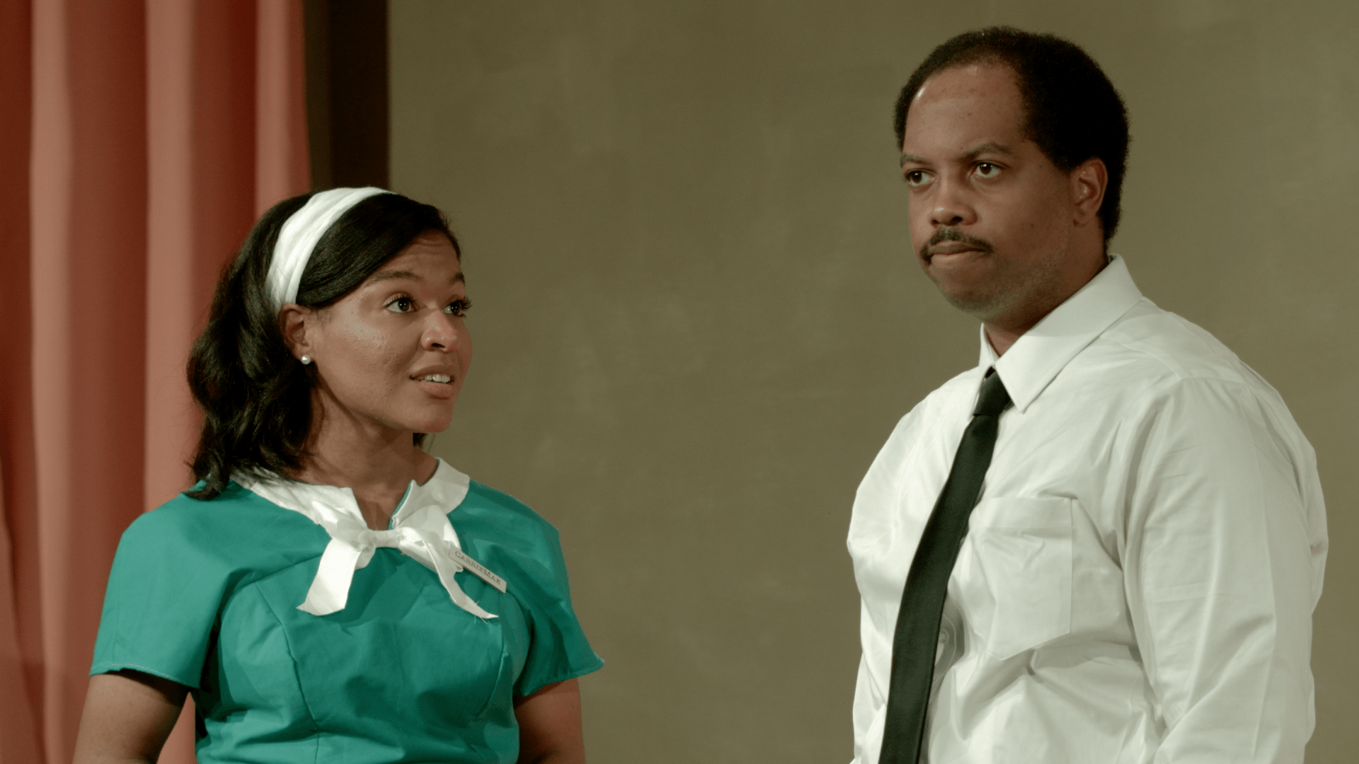A woman in a maid 's uniform is standing next to a man in a white shirt.