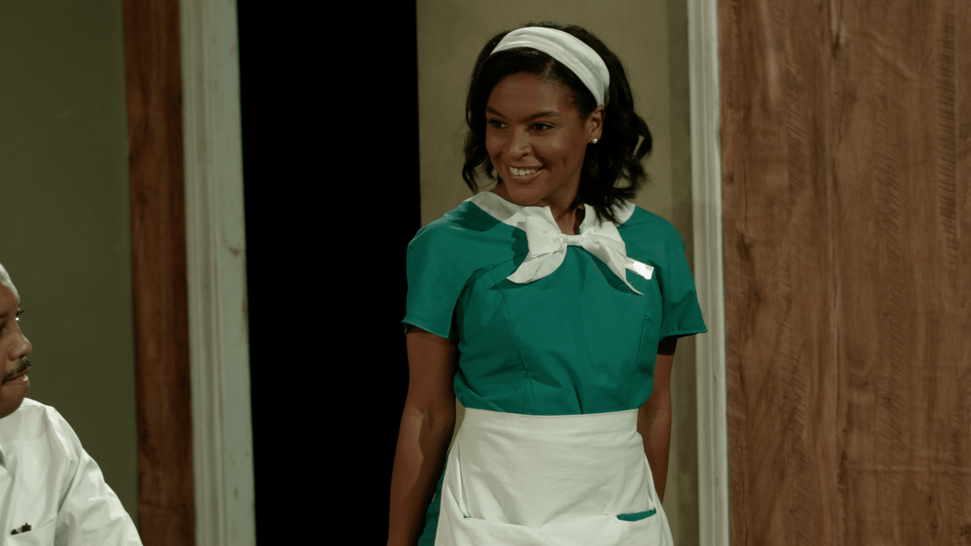 A woman in a maid 's uniform is standing next to a man in a white shirt .